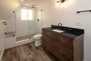 Bathroom with vanity, tiled shower, and dark wood-style floors