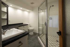 Full bathroom featuring vanity, a stall shower, dark tile patterned flooring, and recessed lighting