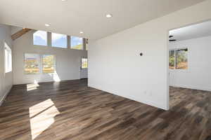 Unfurnished living room featuring recessed lighting, dark wood-style floors, and a high ceiling