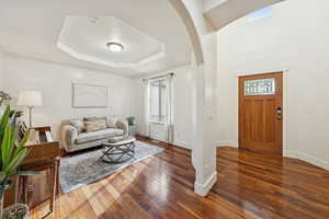 Den / front room featuring arched walkways and a tray ceiling