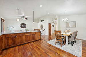 Dining space featuring vaulted ceiling, arched walkways, and a chandelier