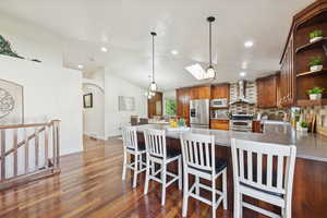 Kitchen with vaulted ceiling, hanging light fixtures, a peninsula, and stainless steel appliances