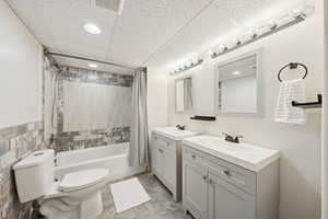 Full bath featuring tiled shower / bath combo and two vanities