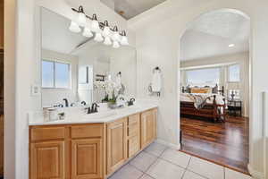 Primary ensuite bathroom featuring double vanity, lots of natural light, and light tile floors