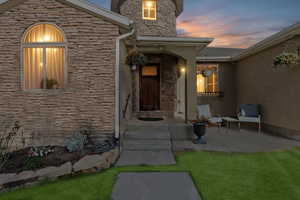 Evening view of exterior entry with stone and stucco siding