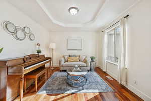 Living area featuring a raised ceiling and hardwood floors