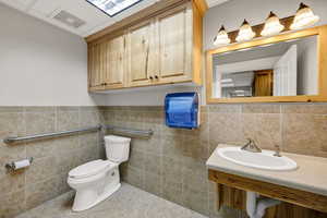 ADA Bathroom featuring tile walls, tile patterned floors, and a wainscoted wall