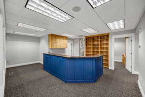 Unfurnished reception area with dark colored carpet and a paneled ceiling