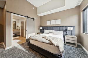 Carpeted bedroom with a barn door and ensuite bathroom