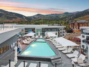 Pool at dusk featuring a mountain view, a community pool, and a patio