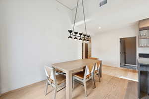 Dining room with light wood finished floors and recessed lighting
