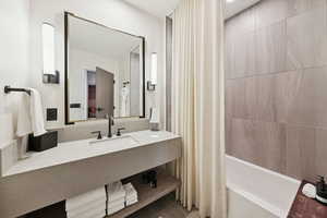 Bathroom featuring vanity and shower / bathtub combination with curtain