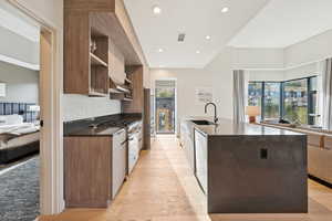 Kitchen with plenty of natural light, dark stone countertops, light wood-style floors, high end appliances, and recessed lighting