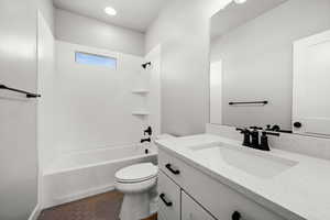 Full bathroom with washtub / shower combination, vanity, dark tile patterned floors, and recessed lighting