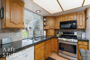 Kitchen with gas range, decorative backsplash, white dishwasher, open shelves, and recessed lighting