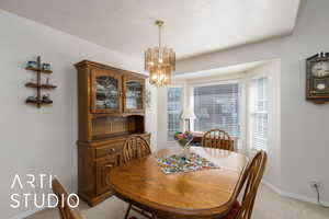 Dining room with light colored carpet and a chandelier