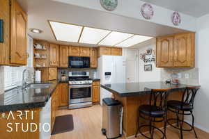 Kitchen with tasteful backsplash, brown cabinets, stainless steel gas range oven, light wood-style flooring, and open shelves