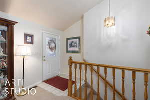 Foyer with vaulted ceiling, light tile patterned floors, and a chandelier