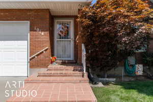 Property entrance with brick siding, an attached garage, and a lawn