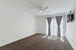 Unfurnished room featuring dark carpet and ceiling fan