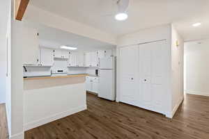 Kitchen with white cabinets, white appliances, dark wood-style floors, a peninsula, and recessed lighting
