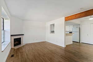 Unfurnished living room featuring dark wood-style flooring and a tile fireplace