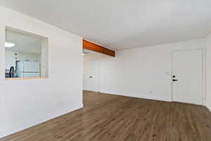 Unfurnished living room with dark wood-style flooring and beamed ceiling