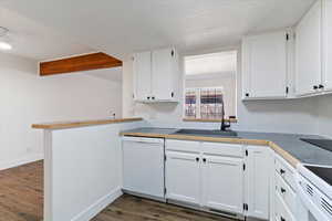 Kitchen featuring white appliances, dark wood finished floors, white cabinetry, and beamed ceiling