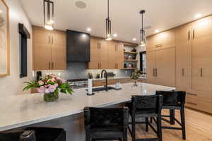 Kitchen featuring a kitchen breakfast bar, open shelves, tasteful backsplash, light stone counters, and pendant lighting