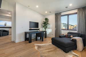 Living room with light wood finished floors, vaulted ceiling, and recessed lighting