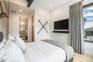 Bedroom featuring wood finished floors, recessed lighting, and connected bathroom