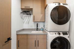 Washroom featuring stacked washer / dryer and cabinet space