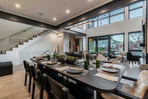 Dining area with stairway, light wood finished floors, recessed lighting, and a high ceiling
