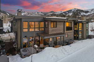 Snow covered rear of property featuring a chimney and a mountain view