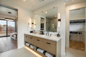 Ensuite bathroom with double vanity, a stall shower, tile patterned floors, and a spacious closet