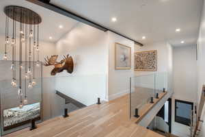 Hall featuring an upstairs landing, wood finished floors, and recessed lighting