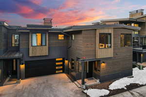 Modern home featuring a chimney, concrete driveway, and a garage