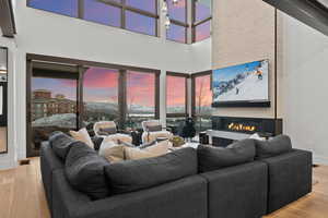 Living area featuring wood finished floors, a towering ceiling, and a glass covered fireplace