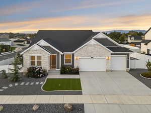 Craftsman inspired home featuring an attached garage, driveway, stone and stucco.
