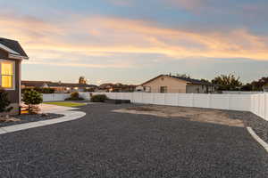 Yard at dusk featuring a fenced backyard and a residential view. This is east side of the back yard