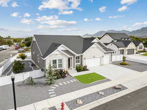 View of front of home featuring stone siding, a mountain view, concrete driveway, a garage, and roof with shingles