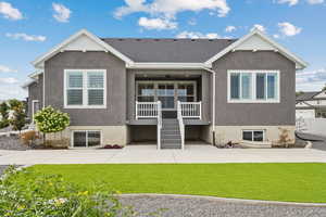 Rear view of property featuring a yard, stucco siding, ceiling fan, &stairs.