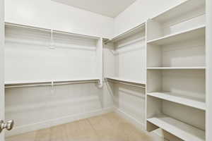 Walk in master closet featuring  custom shelving