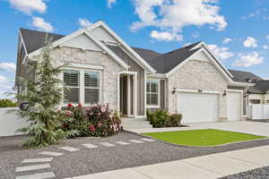 View of front of home featuring stone  and stucco siding, driveway, a garage,