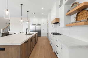 Kitchen featuring white cabinets, light stone countertops, light wood-type flooring, and recessed lighting