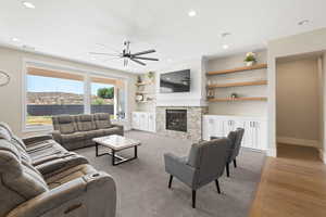 Living room featuring light wood-style floors, recessed lighting, a fireplace, and built in features
