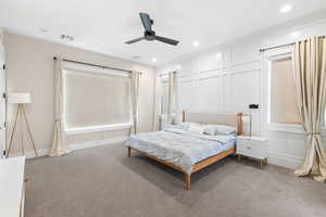 Bedroom with light colored carpet, a decorative wall, a ceiling fan, and recessed lighting