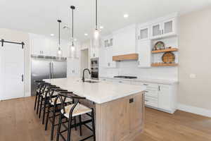 Kitchen with a barn door, white cabinetry, a kitchen bar, built in appliances, and recessed lighting