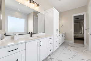 Full bathroom with two vanities, ensuite bath, and light marble finish flooring