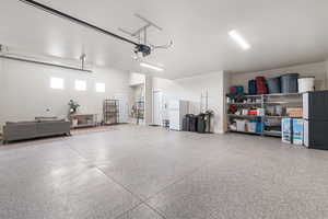 Garage with freestanding refrigerator and a garage door opener
